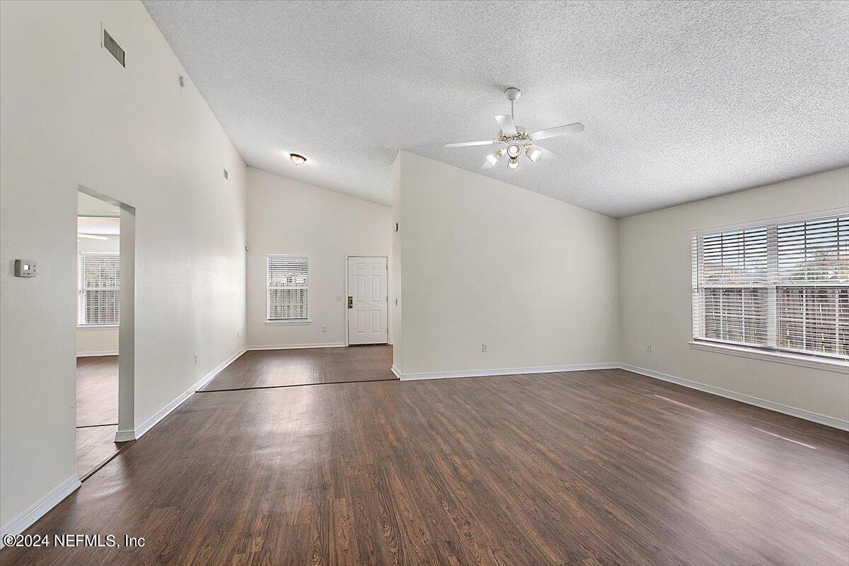 7133 High Bluff Road Jacksonville, FL 32244 - Photo 3 of 17 an empty room with wooden floor chandelier and windows