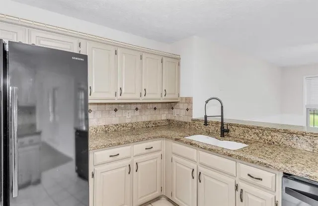 a kitchen with granite countertop a sink and cabinets