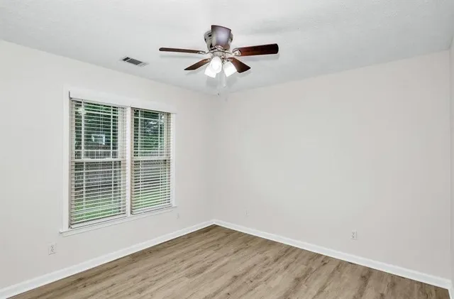 a view of empty room with wooden floor and fan