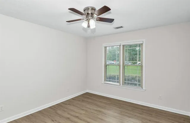 an empty room with wooden floor and windows