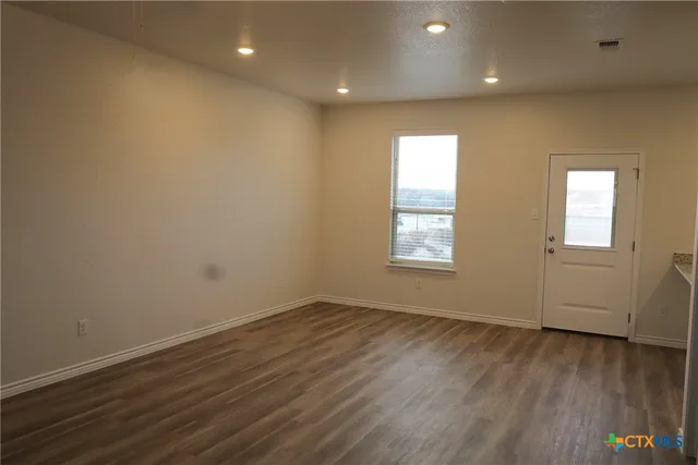 an empty room with wooden floor and windows