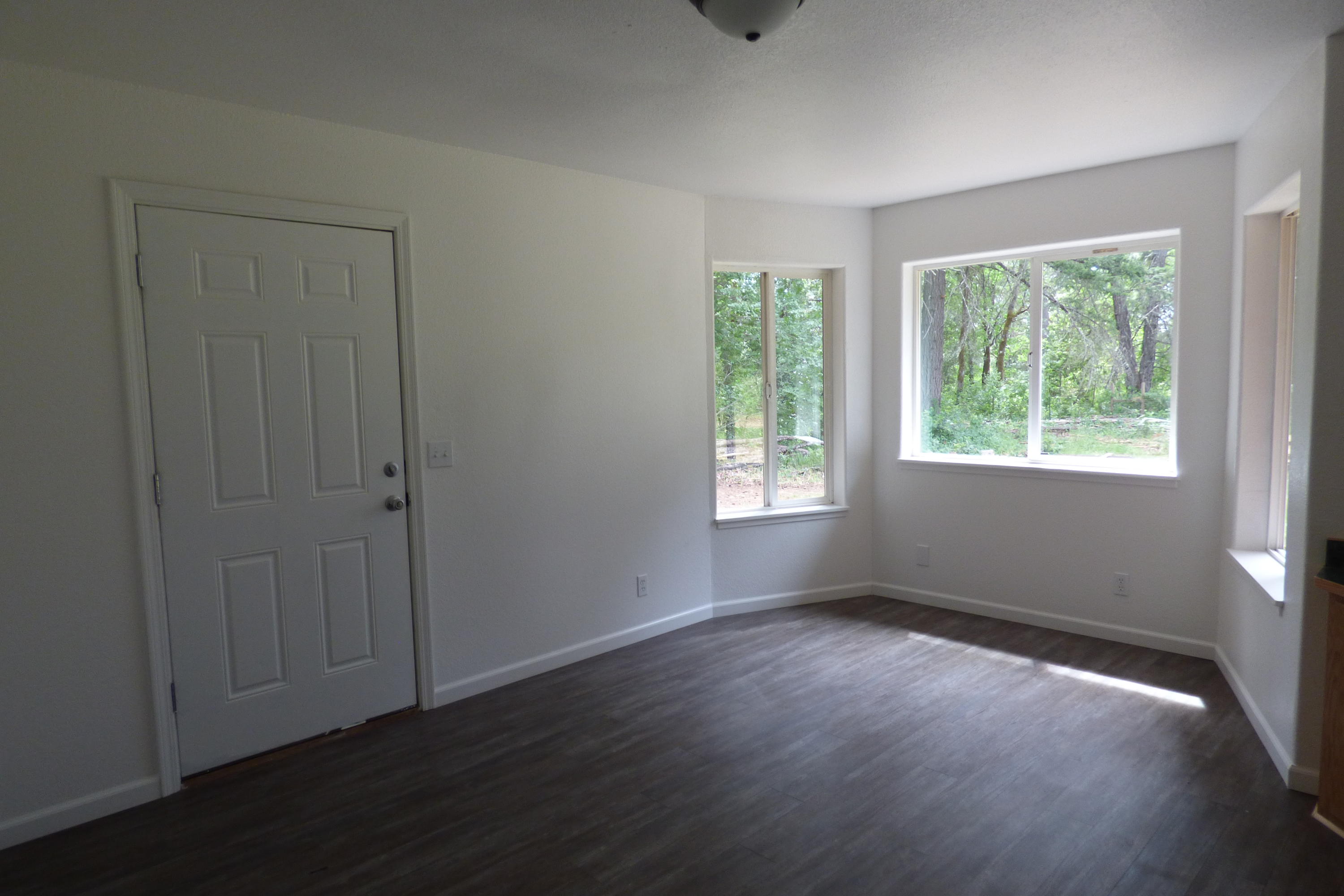 689 Hummingbird Road Cave Junction, OR 97523 - Photo 15 of 23 a view of an empty room with wooden floor and a window