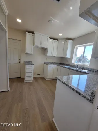 a kitchen with granite countertop a stove a sink and a refrigerator