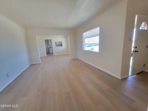 a view of an empty room with wooden floor and a window