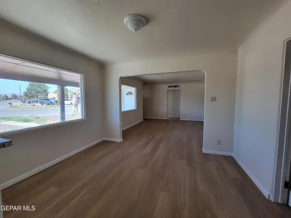a view of an empty room with wooden floor and a window