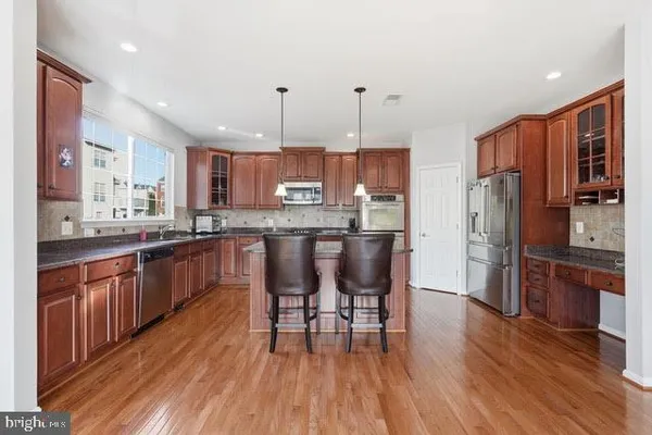 a kitchen with stainless steel appliances granite countertop wooden floors a refrigerator and cabinets