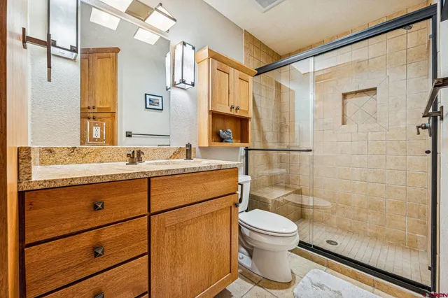 a bathroom with a granite countertop sink toilet a mirror and shower
