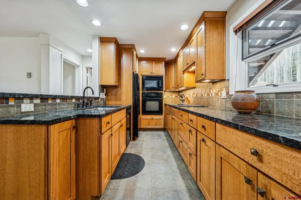 a large kitchen with granite countertop a sink and a stove top oven