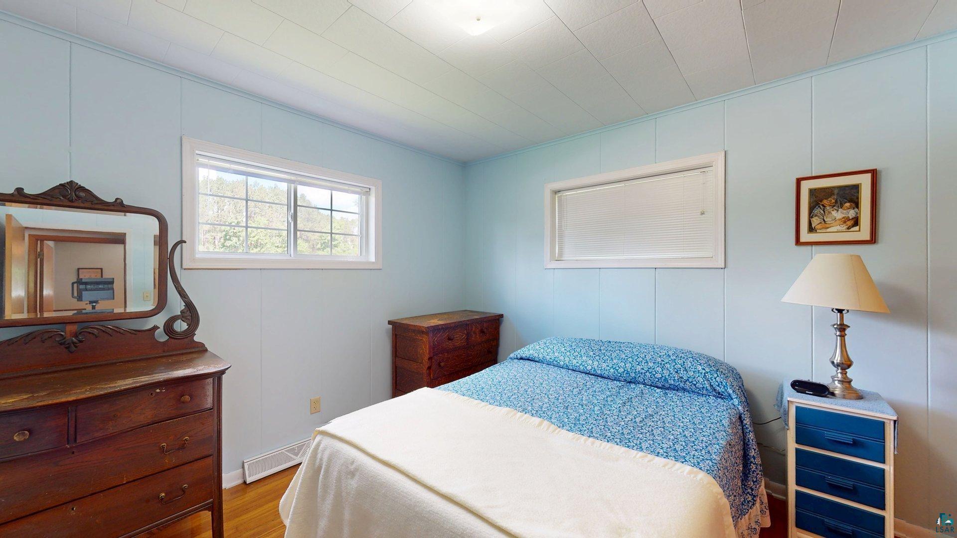 10614 Moose Lake Road Orr, MN 55771 - Photo 27 of 44 Bedroom featuring wood-finish flooring, light blue paneled walls, and a white ceiling