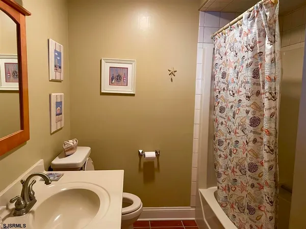 a bathroom with a sink a toilet and shower curtain