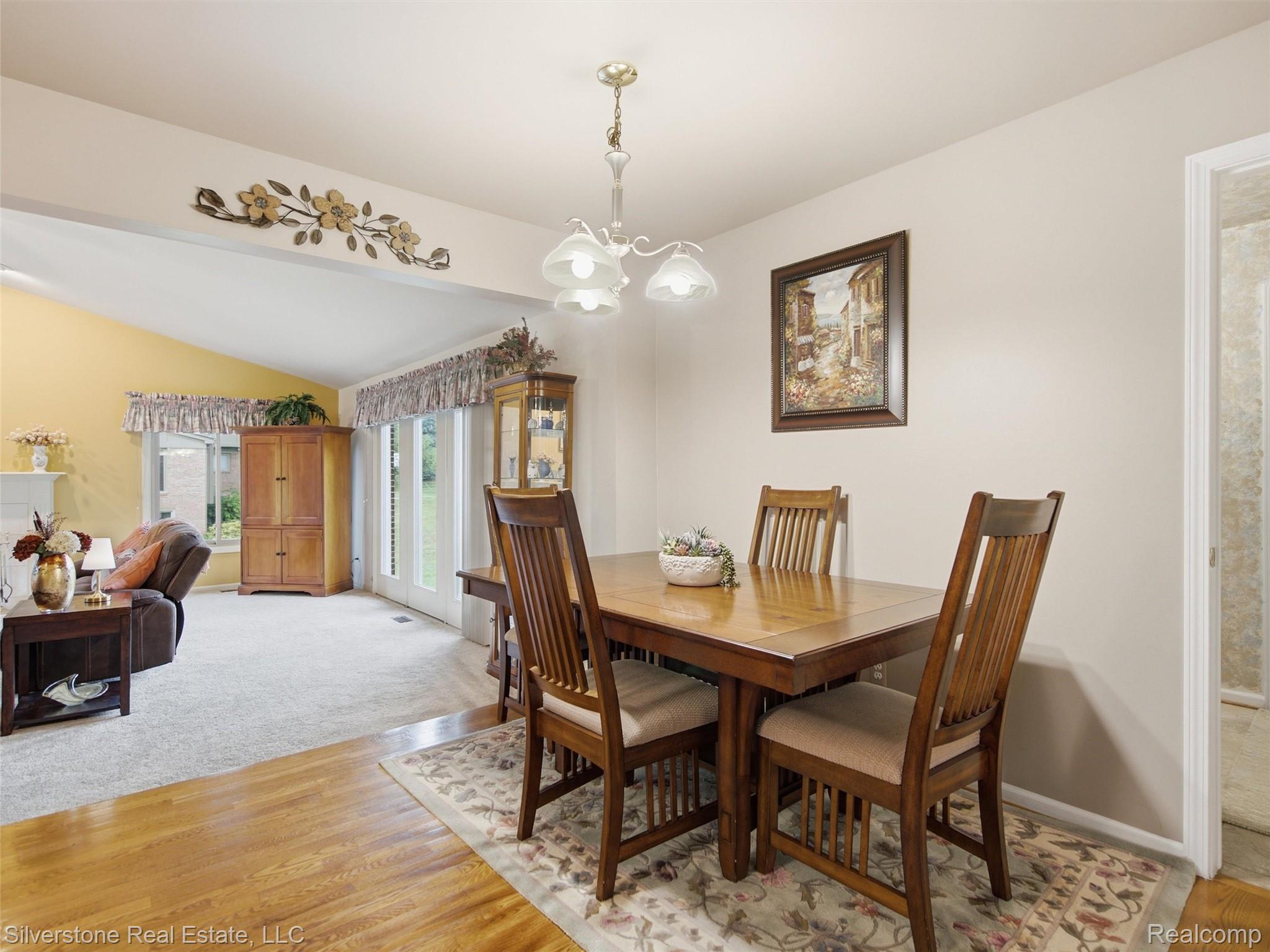 6577 Edith Court Troy, MI 48085 - Photo 27 of 61 Bright dining area featuring wood-finish flooring, a decorative ceiling fixture, and direct access to an expansive living space with vaulted ceilings and large windows