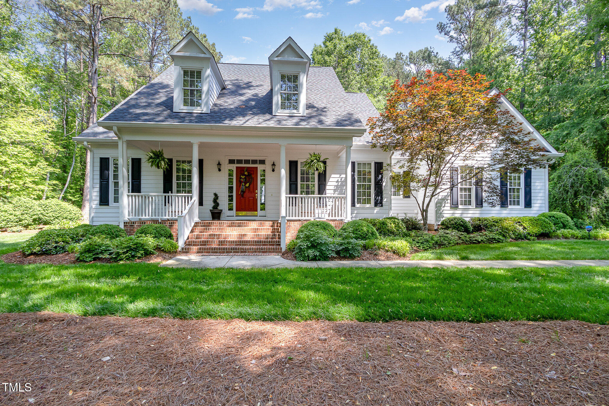 a front view of a house with a yard and potted plants