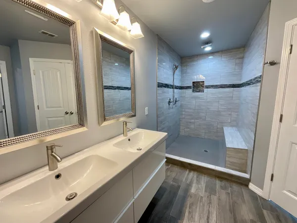 a bathroom with a double vanity sink and mirror with shower