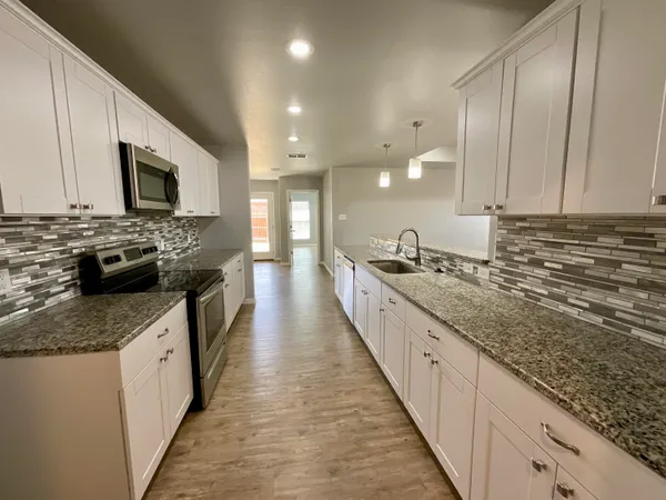 a large kitchen with stainless steel appliances granite countertop a lot of counter space