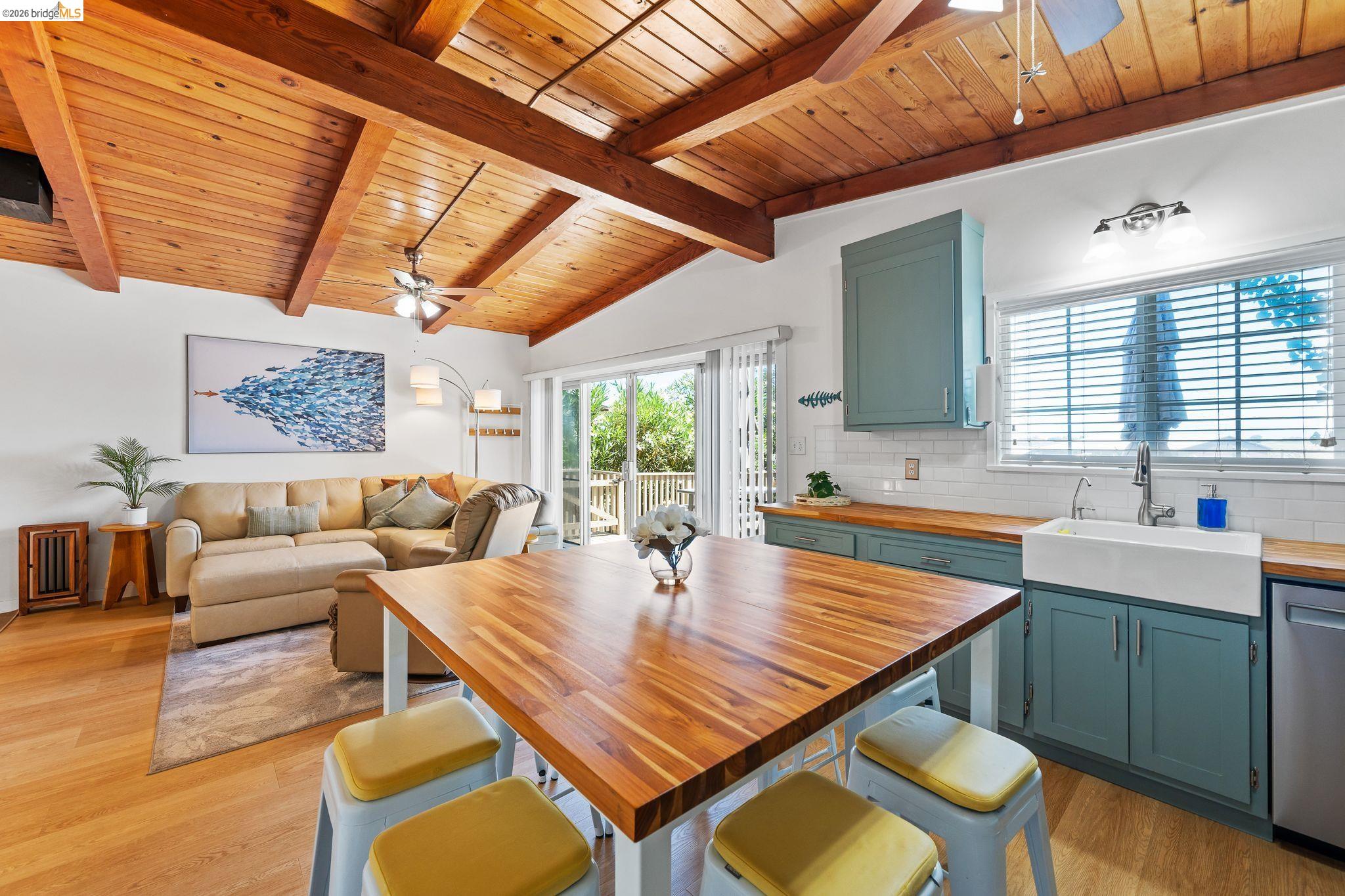 1704 Taylor Road Bethel Island, CA 94511 - Photo 33 of 73 Open concept living space featuring a vaulted wood-plank ceiling with exposed beams, wood-finish flooring, a kitchen with custom-painted cabinetry, wood countertops, and a farmhouse sink