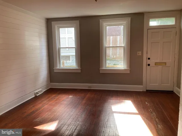 a view of an empty room and wooden floor and window
