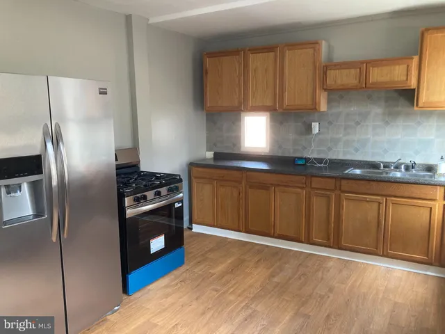 a kitchen with stainless steel appliances granite countertop a stove a refrigerator and a sink with wooden cabinets