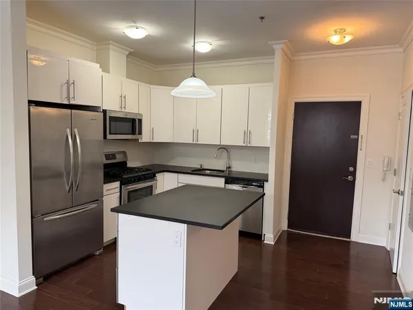 a kitchen with kitchen island a counter space a refrigerator a sink and a stove