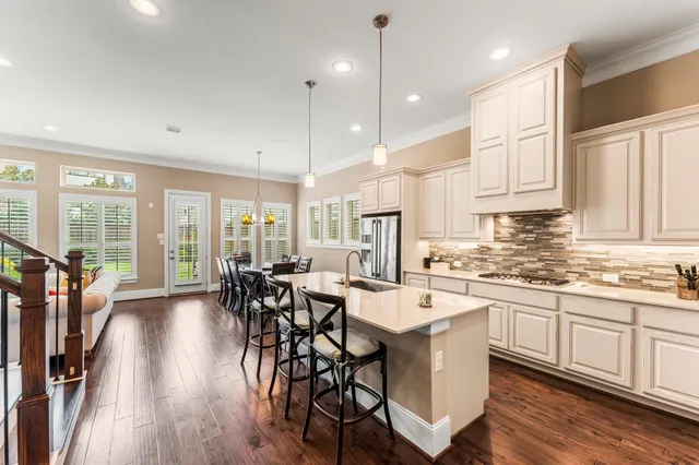 a kitchen with stainless steel appliances a dining table chairs stove and white cabinets