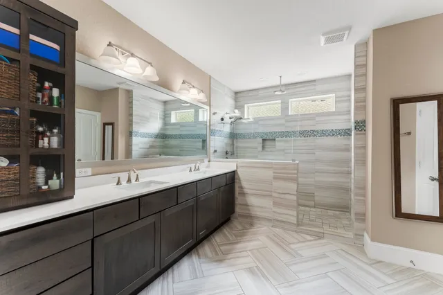 a bathroom with a double vanity sink a toilet a mirror and shower