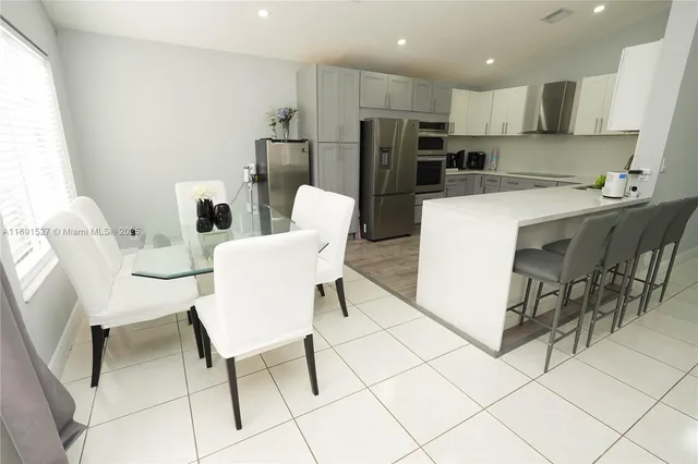a view of kitchen with refrigerator stove dining table and chairs