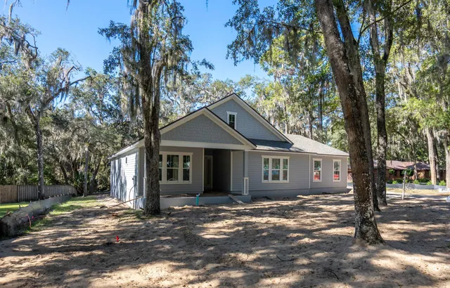 a front view of a house with a yard and large trees