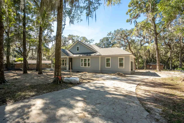 a view of a yard in front of a house with large trees