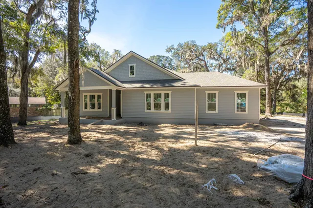 a view of a yard in front of a house with large windows