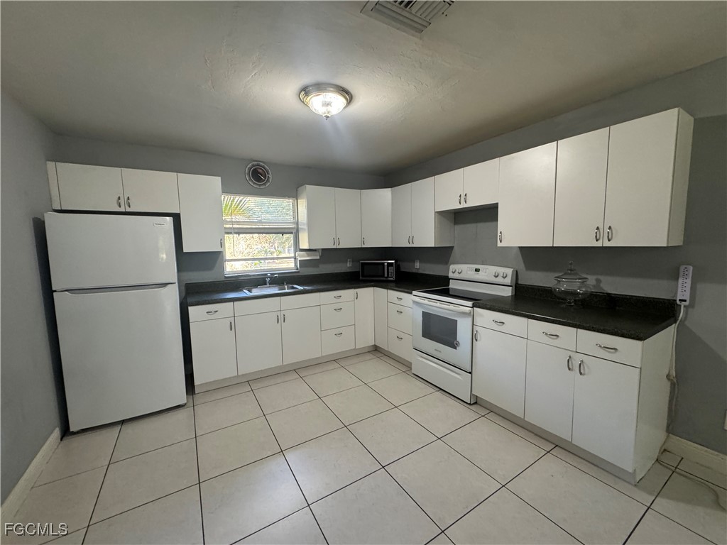 291 16th Street Northeast, Unit 1 Naples, FL 34120 - Photo 9 of 21 a white kitchen with a sink stainless steel appliances and cabinets