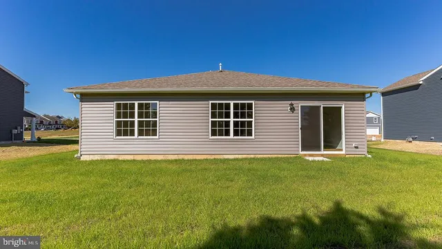 a front view of house with yard and trees in the background