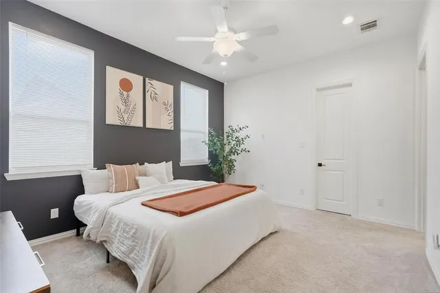 a bedroom with a large bed and a chandelier fan