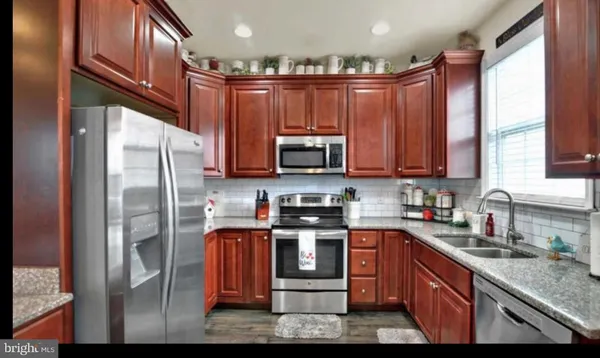a kitchen with stainless steel appliances granite countertop a refrigerator a stove top oven a sink and dishwasher