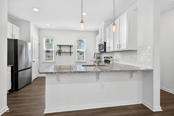 a kitchen with stainless steel appliances granite countertop a sink a stove a refrigerator a center island and wooden cabinets