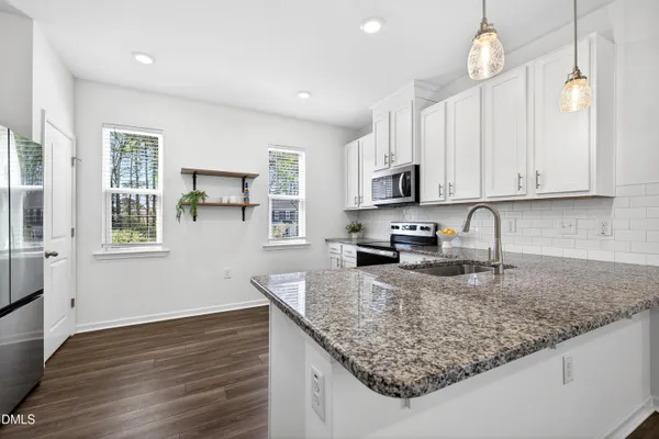 a kitchen with granite countertop a sink a counter space appliances and cabinets