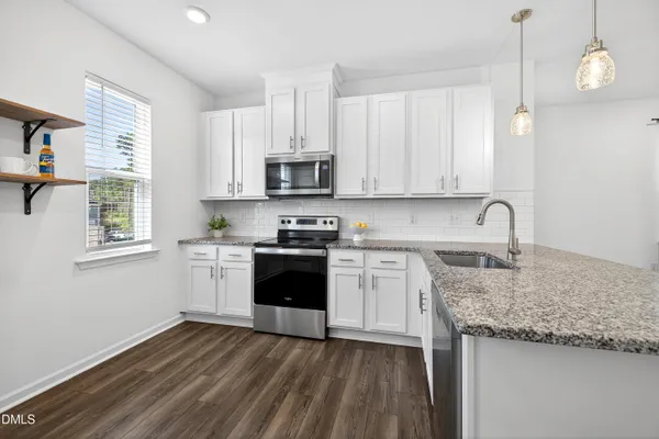a kitchen with kitchen island granite countertop a sink cabinets and stainless steel appliances
