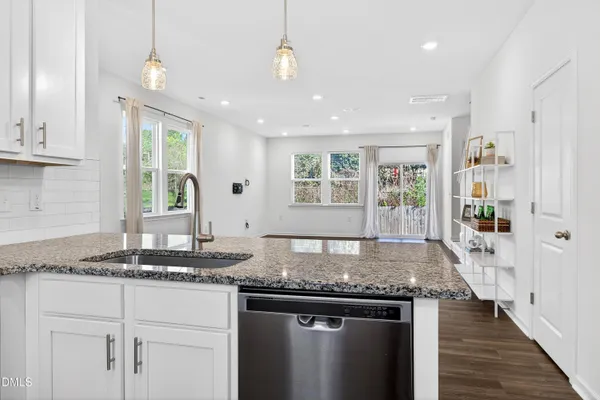 a kitchen with granite countertop kitchen island stainless steel appliances a sink stove and cabinets