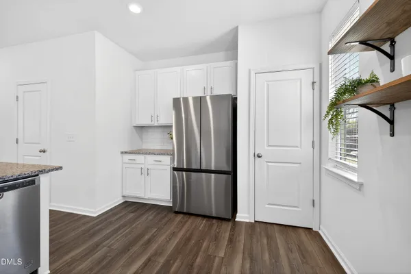 a kitchen with a refrigerator and a wooden floor