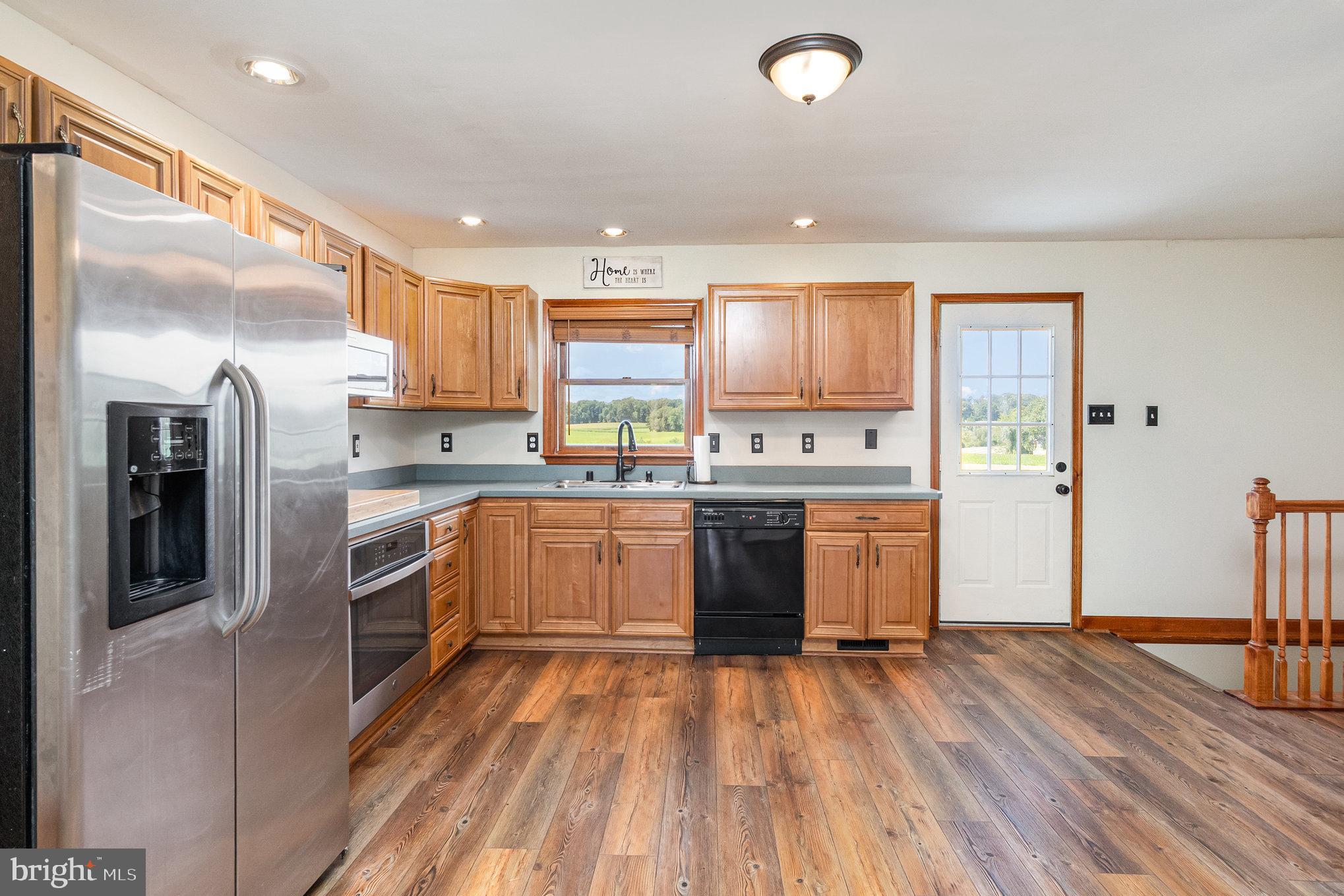 4816 Amos Road White Hall, MD 21161 - Photo 12 of 56 a kitchen with stainless steel appliances granite countertop a refrigerator a sink dishwasher a stove and white countertops with wooden floor