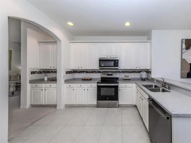 a kitchen with granite countertop white cabinets and stainless steel appliances