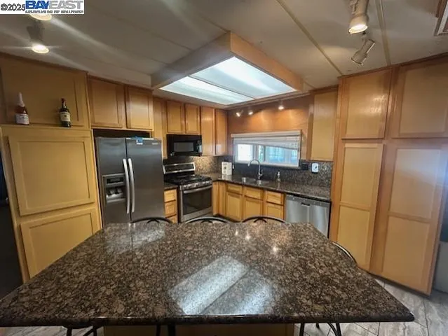 a kitchen with stainless steel appliances granite countertop a refrigerator a stove and a sink