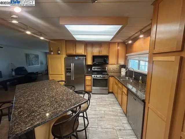 a kitchen with stainless steel appliances granite countertop sink stove refrigerator and cabinets