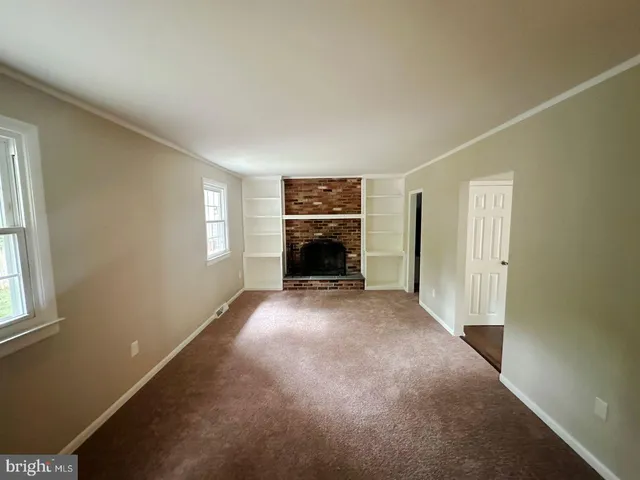an empty room with windows and fireplace