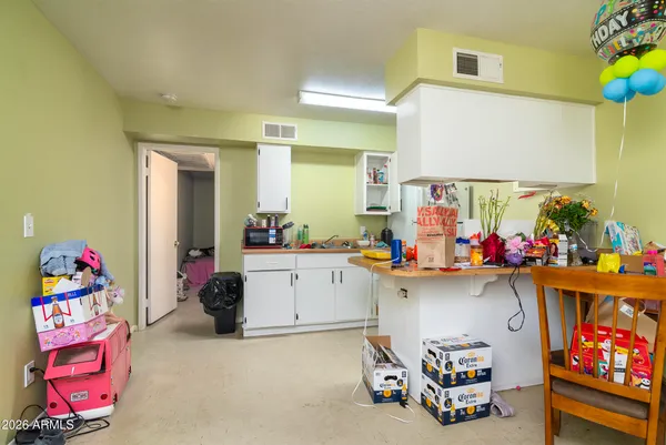 a living room with furniture and a dining table with kitchen appliances