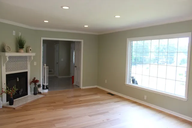 a view of an empty room with a window and wooden floor