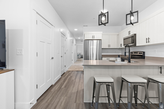 4735 Alder Drive, Unit F101 Mapleton, UT 84664 - Photo 10 of 30 Kitchen featuring pendant lighting, stainless steel appliances, a peninsula, a breakfast bar area, and dark wood-style floors