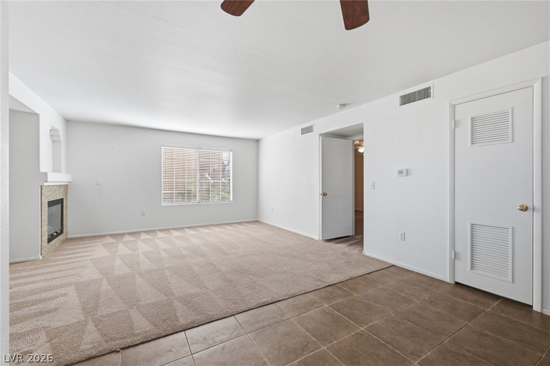 1851 Hillpointe Road, Unit 1311 Henderson, NV 89074 - Photo 9 of 47 Unfurnished living room featuring ceiling fan, light carpet, a tile fireplace, and light tile patterned floors