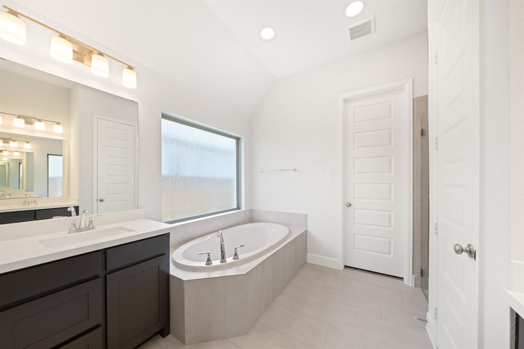 721 Running Iron Trail Mansfield, TX 76063 - Photo 12 of 23 a bathroom with a bathtub a sink a mirror and a shower