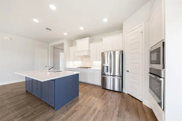 a kitchen with stainless steel appliances granite countertop a refrigerator and a stove top oven