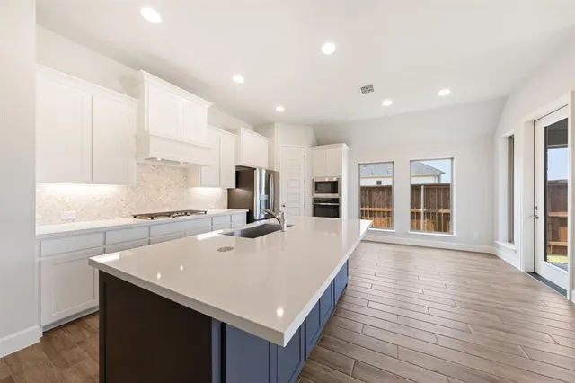 a large kitchen with kitchen island a stove a sink a refrigerator and cabinets