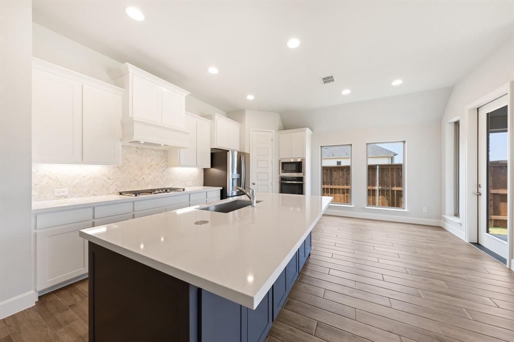 721 Running Iron Trail Mansfield, TX 76063 - Photo 8 of 23 a large kitchen with kitchen island a stove a sink a refrigerator and cabinets